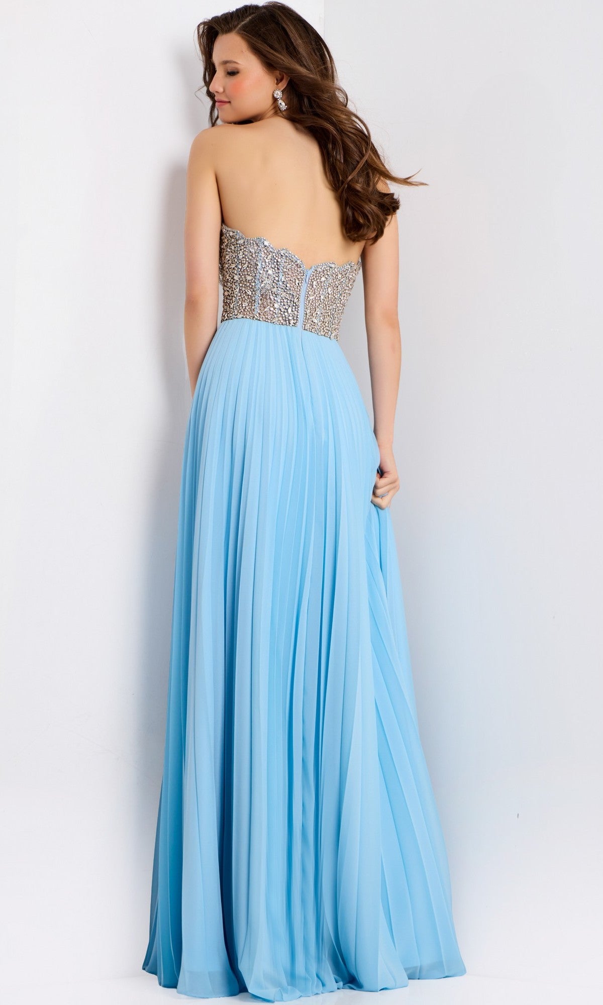 Woman wearing the Jovani 44358 long prom dress with a strapless beaded bodice and flowing light blue chiffon A-line skirt, shown from the back.